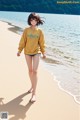 A woman walking on a beach next to the ocean.