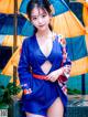 A woman in a blue kimono posing for a picture.