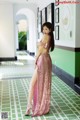 A woman in a pink dress standing in a hallway.