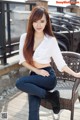 A woman sitting on top of a chair on a patio.