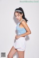 A woman in a blue top and white shorts posing for a picture.