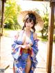 A woman in a blue kimono holding an umbrella.