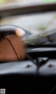 A blurry image of a person sitting in a car.