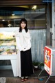 A woman standing in front of a store with a sign.