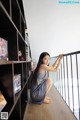 A woman sitting on the floor next to a book shelf.