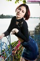 A woman in a black top and a denim skirt posing for a picture.